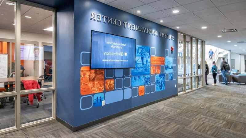 A view from outside the Student Involvement Center with students sitting inside and walking in the distance